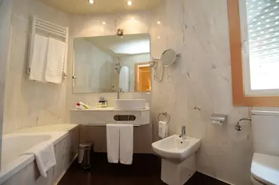 a white bathroom with a tub and a sink at Hotel Spa Congreso in Teo