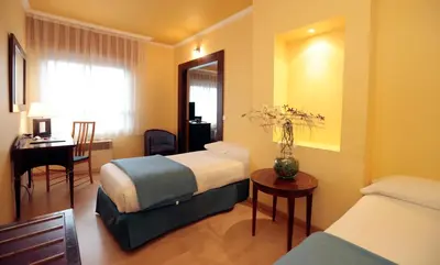 a hotel room with two beds and a table and a desk at Hotel Spa Congreso in Teo