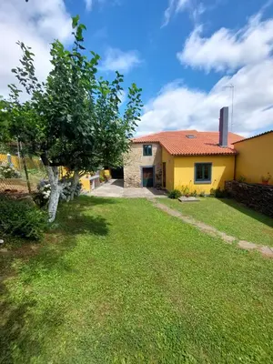 a yellow house with a tree in the yard at Casas de Maragouzos in Silleda