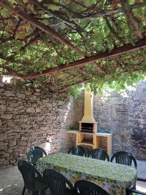 a table and chairs in a room with a stone wall at Casas de Maragouzos in Silleda