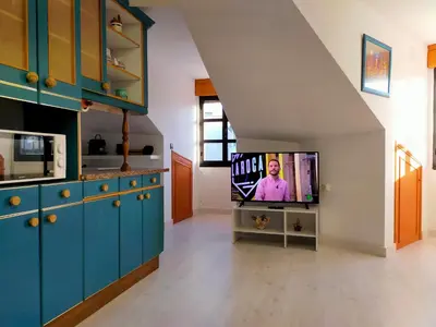 a kitchen with blue cabinets and a flat screen tv at Apartamento en el casco antiguo de Ponferrada in Ponferrada