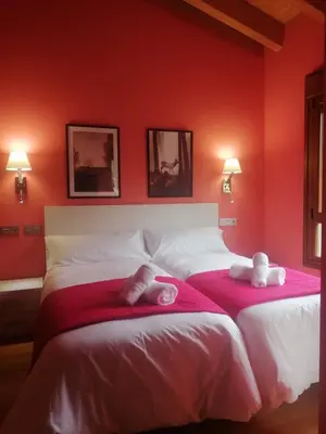 two beds in a bedroom with red walls at PENSIÓN RÚSTICA SANTA MARIÑA DA PONTE in Santa Marina del Puente