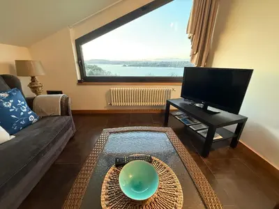 a living room with a couch and a large window at A Marola By Oktheway in Puentedeume