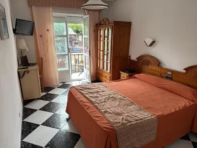 a bedroom with a bed and a window and a television at Hotel Mediante in Ribadeo