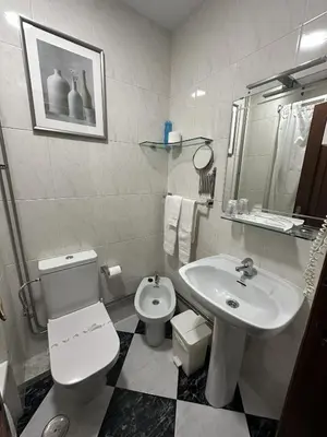 a white bathroom with a toilet and a sink at Hotel Mediante in Ribadeo
