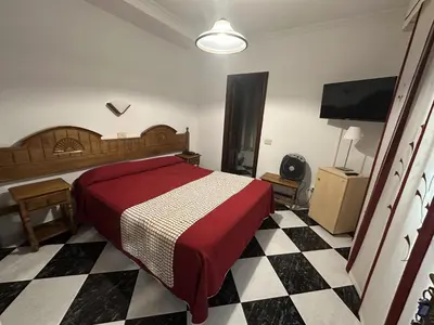 a bedroom with a red bed and a checkered floor at Hotel Mediante in Ribadeo