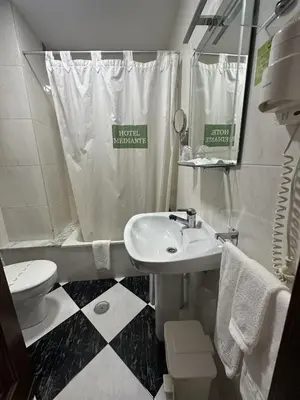 a white bathroom with a sink and a toilet at Hotel Mediante in Ribadeo