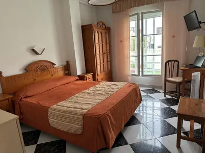 a bedroom with a bed and a desk and a window at Hotel Mediante in Ribadeo