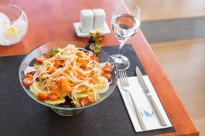 a bowl of salad on a table with wine glasses at Eurostars San Lazaro in Santiago de Compostela