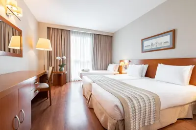 a hotel room with two beds and a desk at Eurostars San Lazaro in Santiago de Compostela