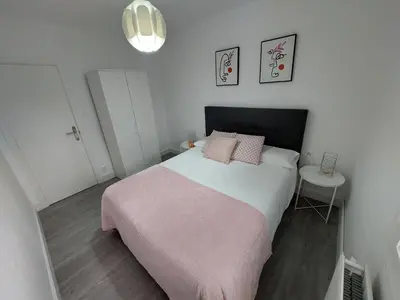 a small bedroom with a large bed with pink pillows at Acea Nova 2 in Monforte de Lemos