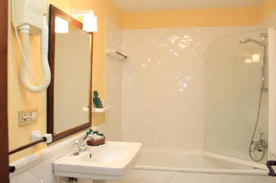 a white bathroom with a sink and a shower at Hotel Virxe da Cerca by Pousadas de Compostela in Santiago de Compostela