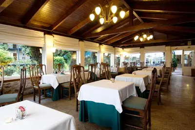 a restaurant with white tables and chairs and a chandelier at Hotel Virxe da Cerca by Pousadas de Compostela in Santiago de Compostela