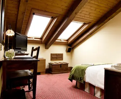 a bedroom with a bed and a desk with a computer at Hotel Virxe da Cerca by Pousadas de Compostela in Santiago de Compostela