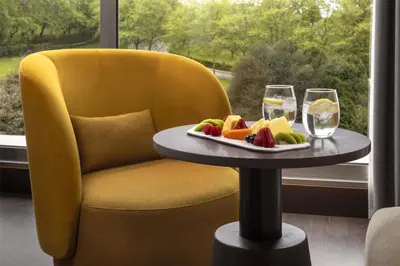 a table with a plate of fruit and two glasses of wine at NH Collection Santiago de Compostela in Santiago de Compostela