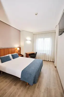 a hotel room with a large bed and a desk at Hotel Ciudad de Compostela in Santiago de Compostela