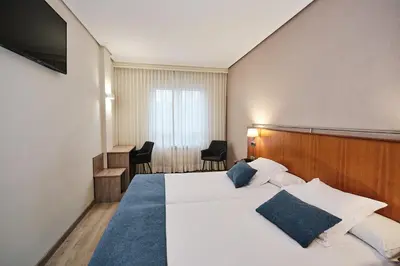 a hotel room with a bed and a television at Hotel Ciudad de Compostela in Santiago de Compostela