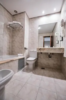 a bathroom with a toilet and a sink and a tub at Hotel Ciudad de Compostela in Santiago de Compostela
