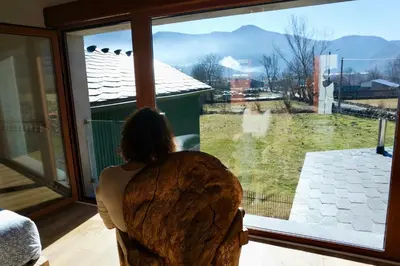 a woman sitting in a chair looking out of a window at El Parreiro VUT-LE-1607 in Villablino