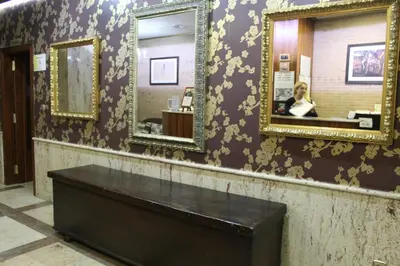 a woman in a bathroom with two mirrors on a wall at Hotel El Castillo in Ponferrada