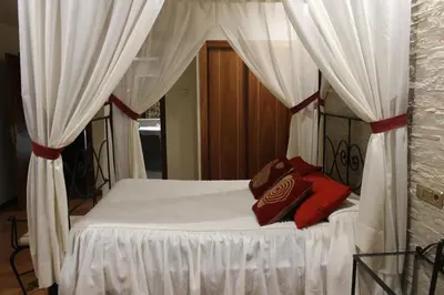 a bedroom with a bed with white curtains and red pillows at Hotel El Castillo in Ponferrada