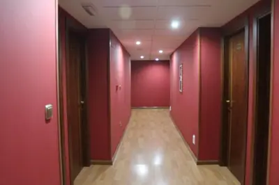 an empty hallway with red walls and wooden floors at Hotel El Castillo in Ponferrada