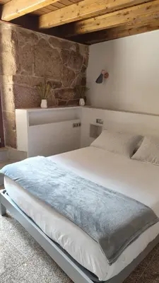 a bedroom with a large white bed with wooden ceilings at Casa Vilar de Flores in Ourense