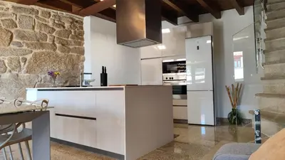 a kitchen with white cabinets and a stone wall at Casa Vilar de Flores in Ourense