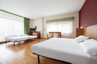 a hotel room with two beds and a table at Exe Vía Argentum in Silleda