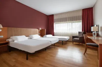 a hotel room with two beds and a desk at Exe Vía Argentum in Silleda
