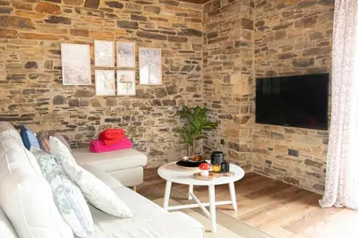 a living room with a brick wall and a tv at CASA EL TEIXO in Taramundi
