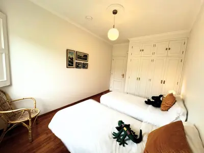 two beds in a room with white walls and wooden floors at Casa Mato in Monforte de Lemos