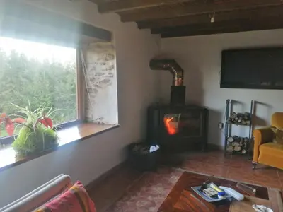 a living room with a wood stove and a window at Casa de piedra en pequeña aldea de Ortigueira in Nieves