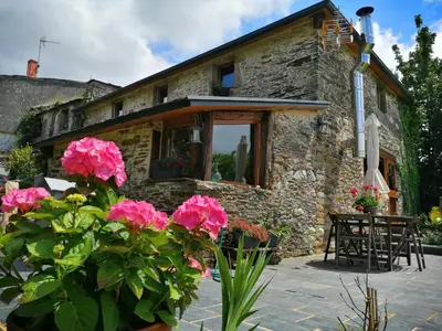 a stone house with flowers in front of it at Casa de piedra en pequeña aldea de Ortigueira in Nieves