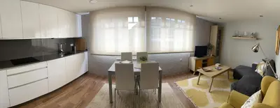 a kitchen and living room with a table and a couch at Apartamento en el centro de Viveiro in Vivero