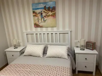 a bedroom with a bed with two white nightstands at Apartamento en el centro de Viveiro in Vivero