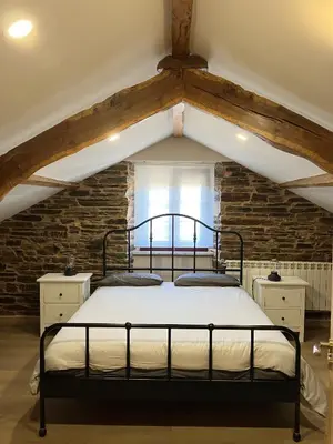 a bedroom with a black bed in a attic at A Casa da Fonte in Santa Eulalia de Oscos