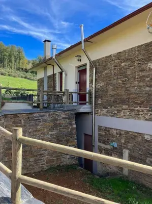 a brick house with a fence in front of it at A Casa da Fonte in Santa Eulalia de Oscos