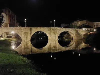 a stone bridge over a river at night at Acea Nova 1 in Monforte de Lemos