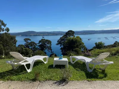 two chairs and a table with a view of the water at CASA FONTE DA PEDREIRA in Sada