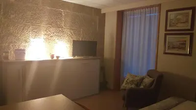 a living room with a tv and a chair and a window at Loft Plaza Mayor in Ourense