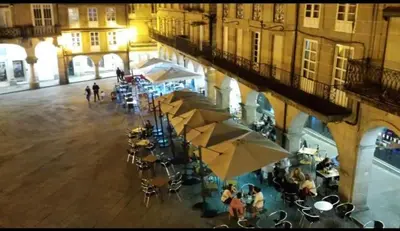 a group of people sitting at tables with umbrellas at Loft Plaza Mayor in Ourense
