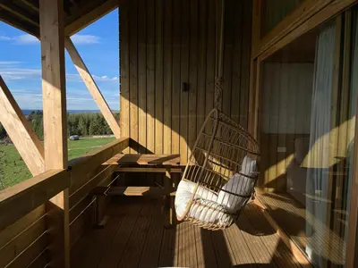 a rocking chair on the porch of a cabin at Olladas de Barbeitos in Fonsagrada