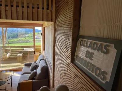 a room with couches and a sign on a wall at Olladas de Barbeitos in Fonsagrada