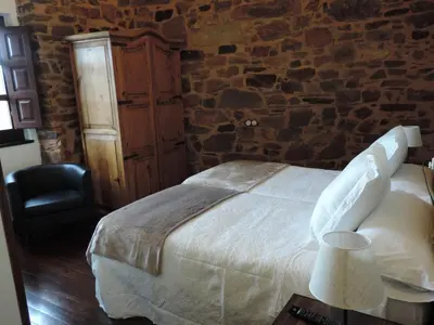 a bedroom with a bed and a stone wall at El Rincón Maragato in Castrillo De Los Polvazares