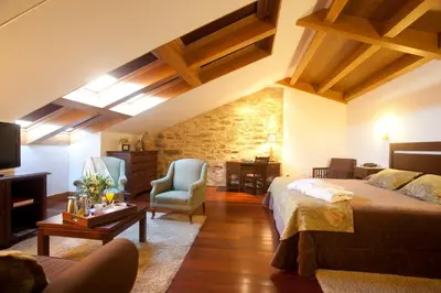 a bedroom with a bed and a living room at San Francisco Hotel Monumento in Santiago de Compostela