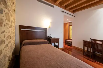 a bedroom with a bed and a table and a window at San Francisco Hotel Monumento in Santiago de Compostela