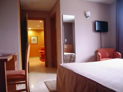 a bedroom with a bed and a room with a television at Apartamentos Ciudad de Lugo in Lugo