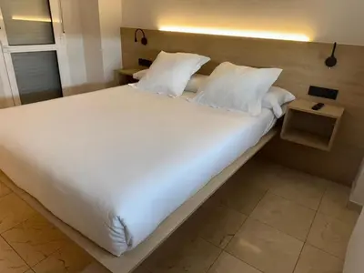 a large bed with white sheets and pillows at Apartamentos Ciudad de Lugo in Lugo