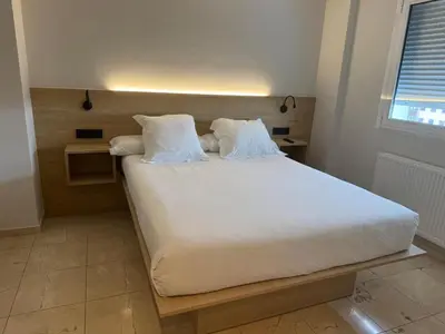 a bed with white sheets and pillows in a room at Apartamentos Ciudad de Lugo in Lugo